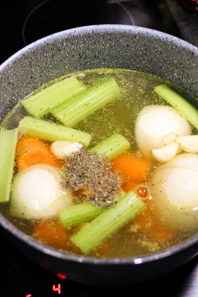Veggies and herbs simmering in chicken broth on the stove. 