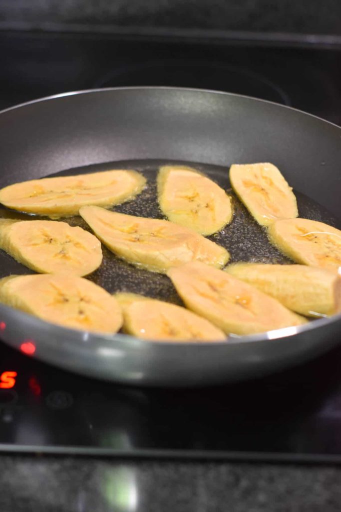 Plantains frying in a skillet with oil. 
