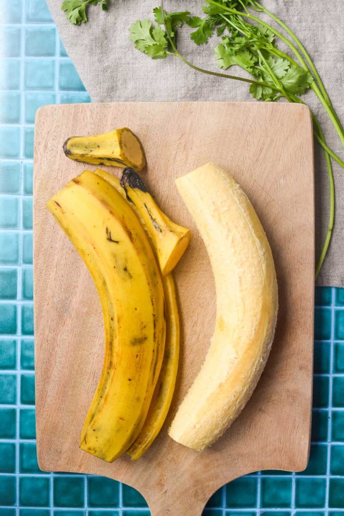 Plantain on a cutting board with peel next to it. 