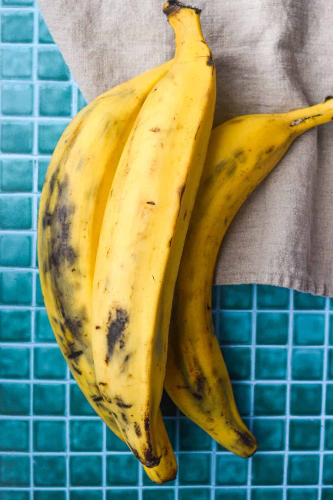 Three ripe plantains on a tile background. 