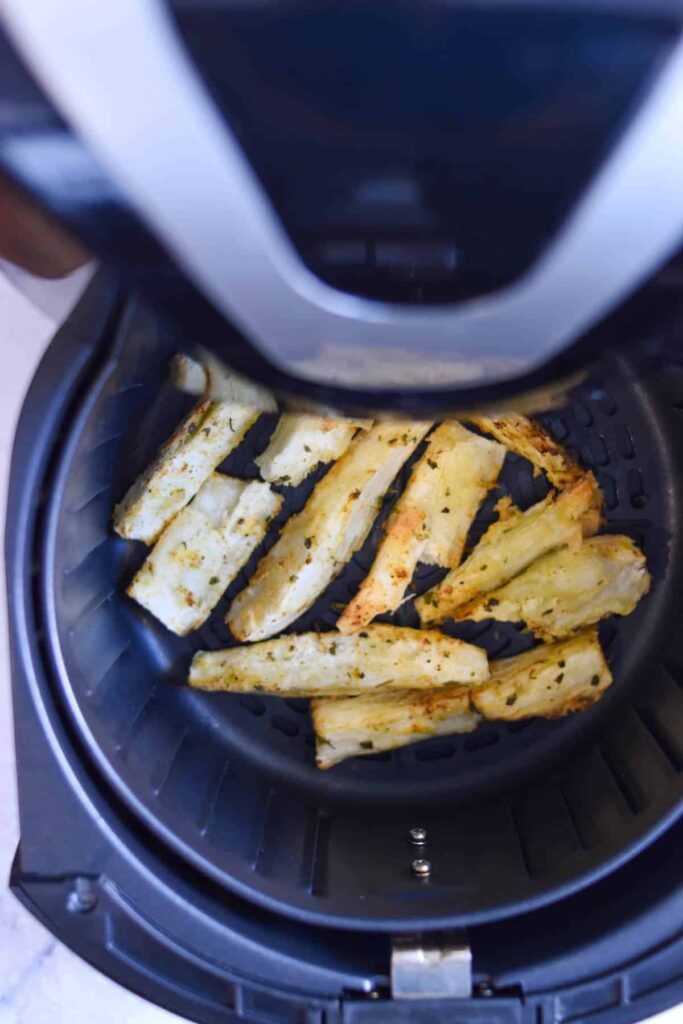 Air fryer yuca fries in the air fryer basket after being cooked. 