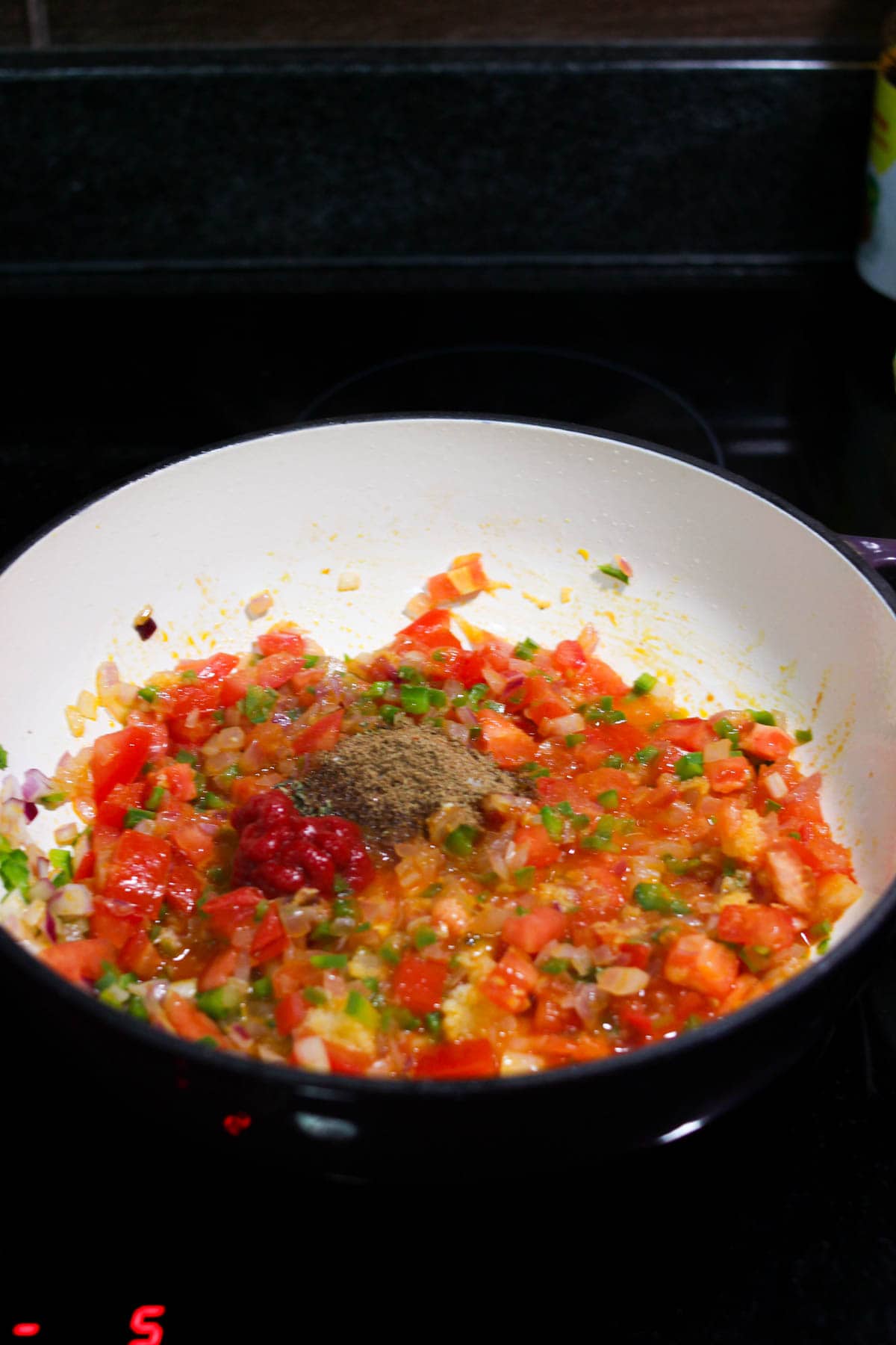 Diced veggies and spices in the dutch oven on the stove. 