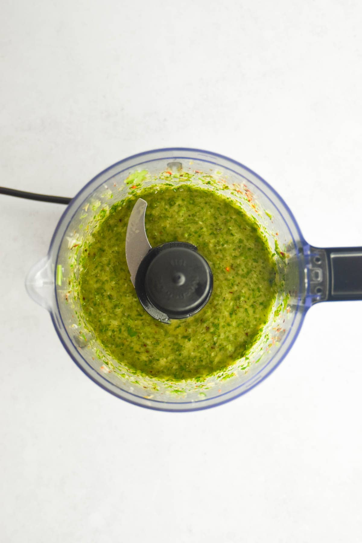 Cilantro chimichurri in a food procoessor after being blended.