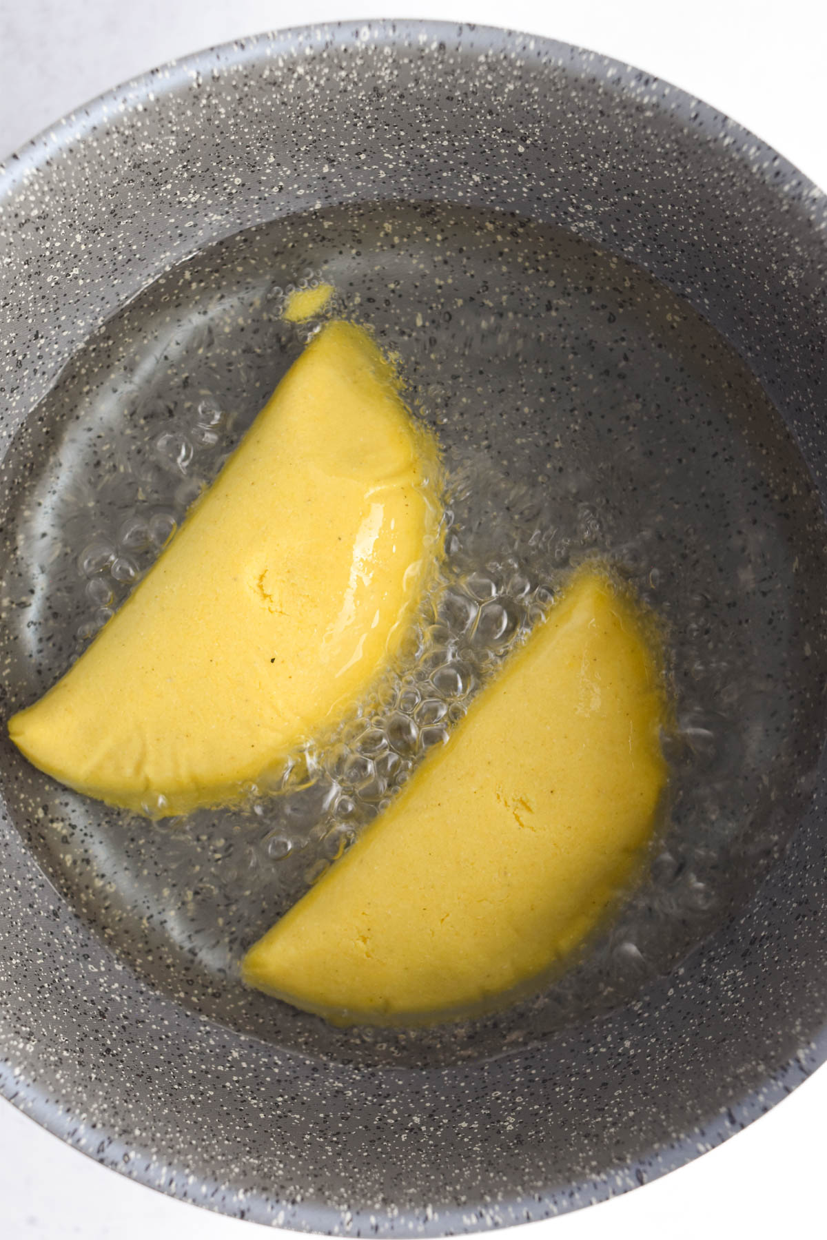 Empanadas being fried in the oil in the pot. 