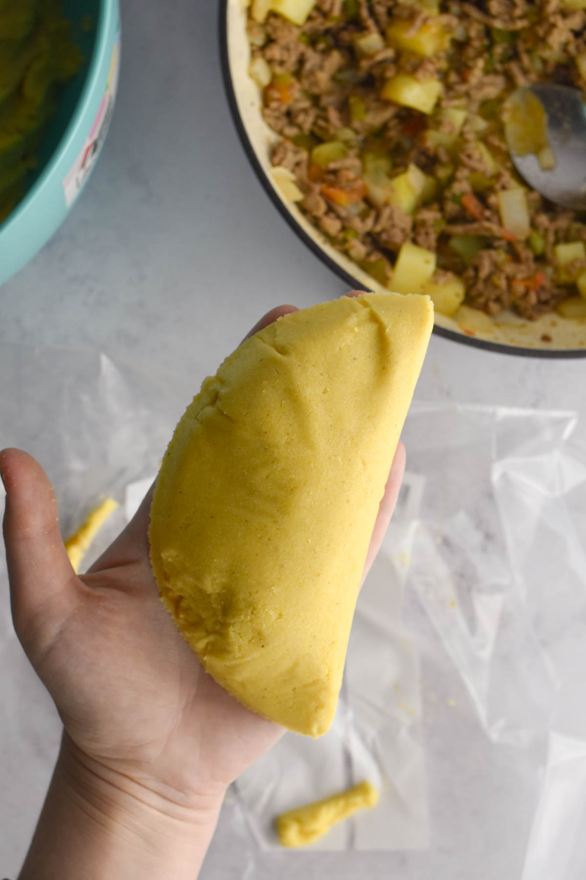 Hand holding the assembled Colombian empanada before it is fried. 