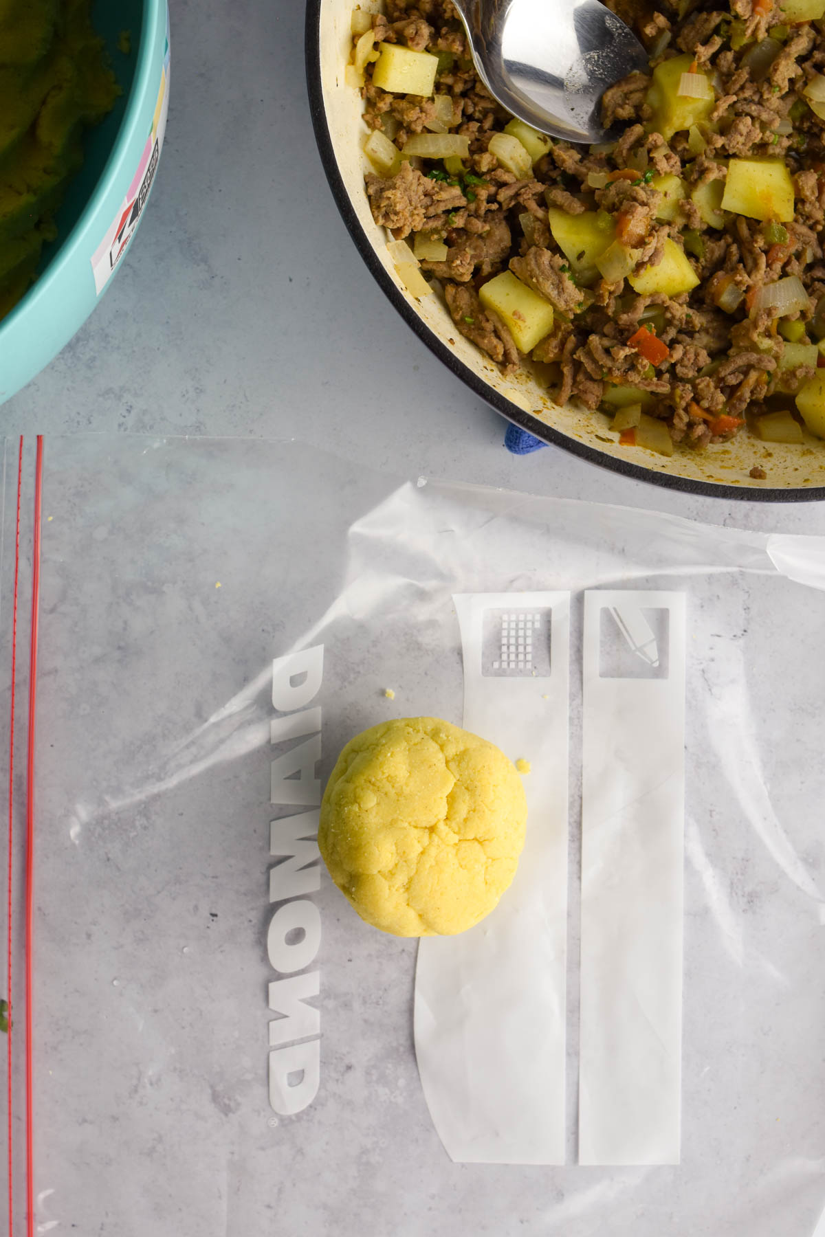 Ball of empanada dough in between a ziplock bag. 