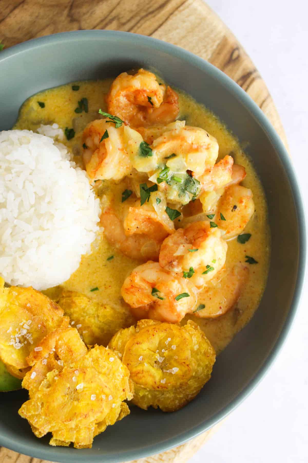 Camarones al ajillo in a bowl with rice and plantains.