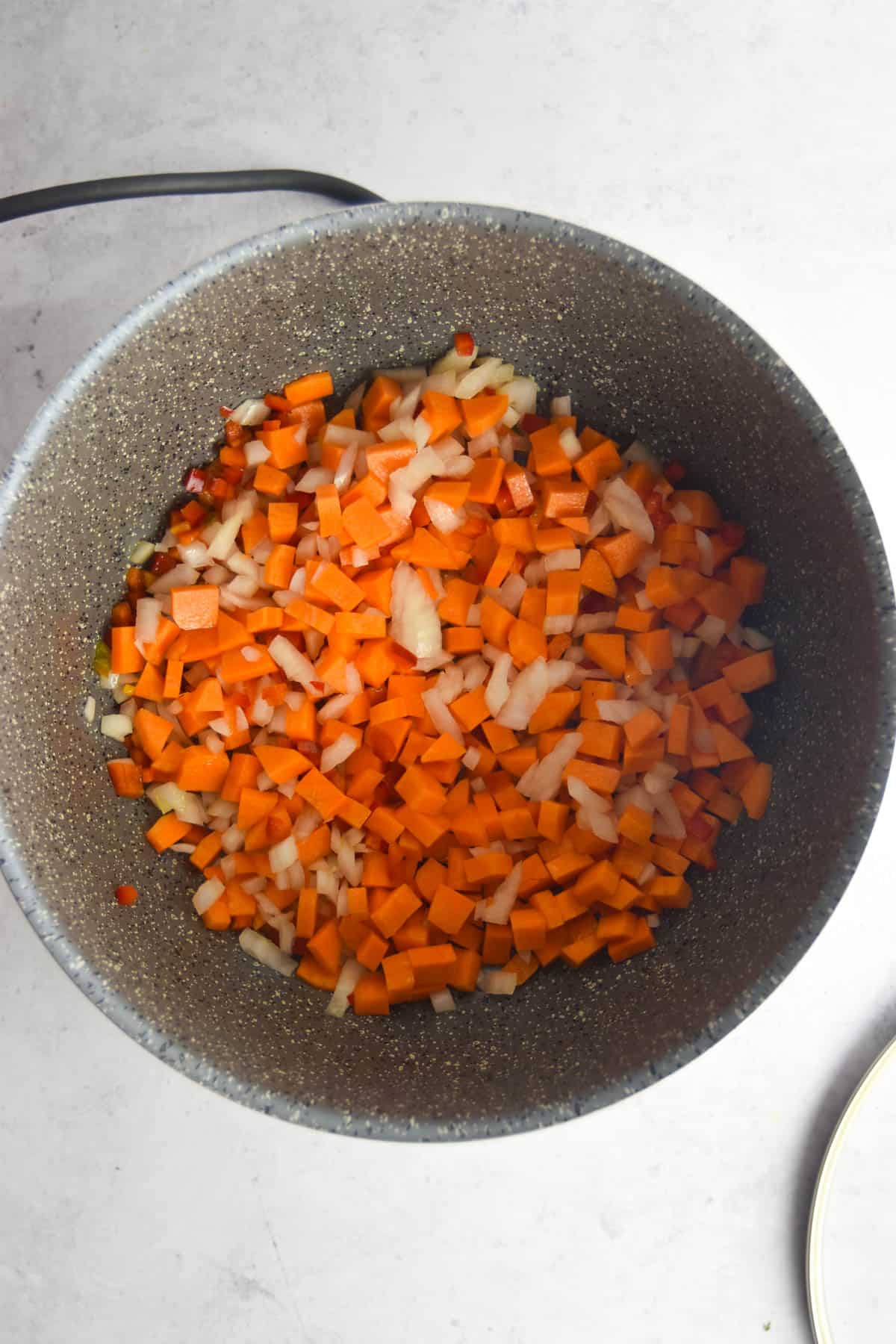 Carrots, onions and red bell pepper added to a stock pot to sauté.