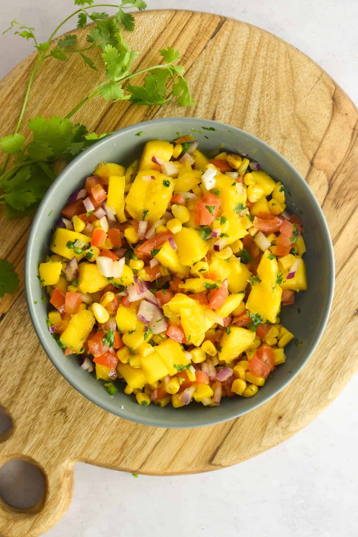 Overhead shot of corn mango salsa on a wooden background.