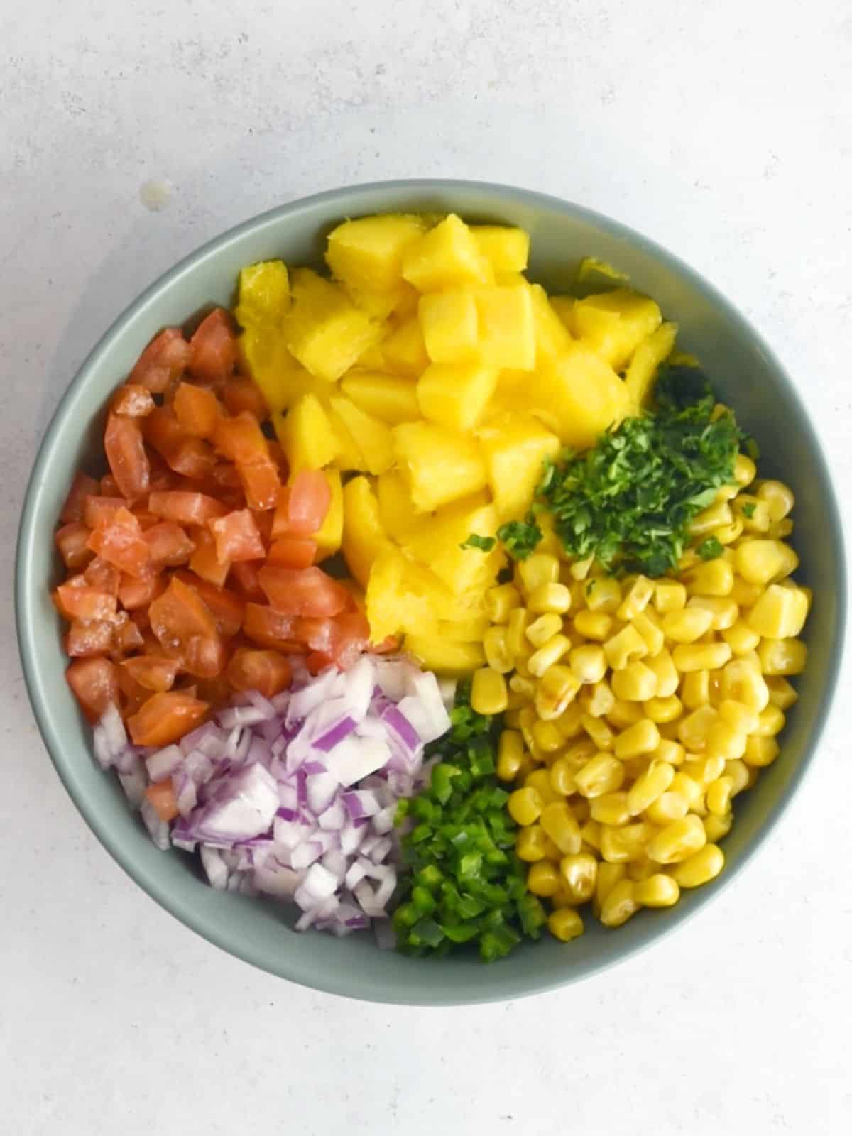 All ingredients for mango salsa prepped and sliced and placed in a bowl.