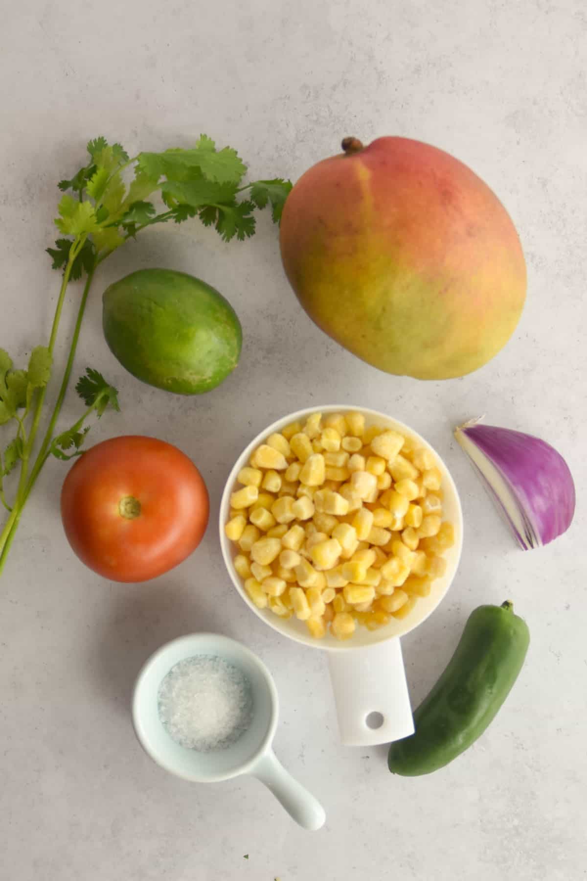 Ingredients needed for corn mango salsa on a counter.